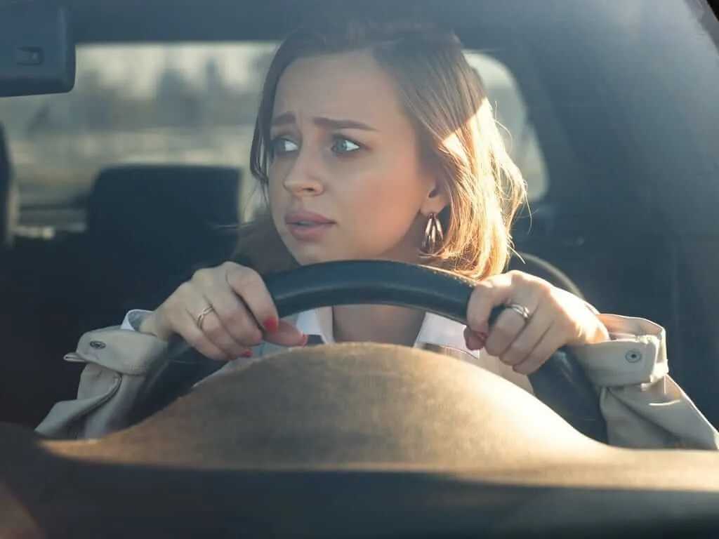 A learner driver looking anxious at the wheel during a lesson